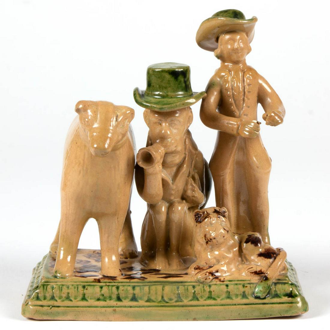 ENGLISH STAFFORDSHIRE CERAMIC FIGURAL GROUP: ENGLISH STAFFORDSHIRE CERAMIC FIGURAL GROUP, having rectangular base, featuring a standing bear, a monkey wearing a green-glazed top hat and blowing a horn, a standing gentleman wearing a green hat wi