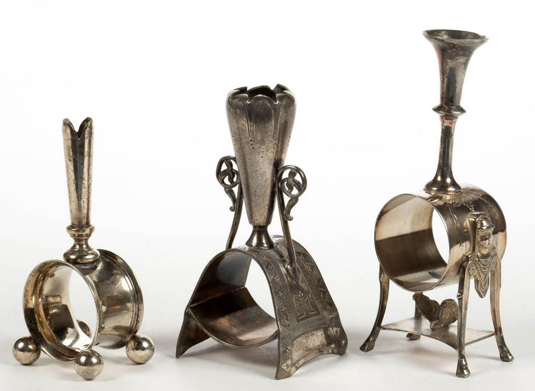 AURORA SILVER PLATE MFG. CO. AND OTHER SILVER-PLATED: AURORA SILVER PLATE MFG. CO. AND OTHER SILVER-PLATED NAPKIN RING BUD VASES, LOT OF THREE, comprising a number "45" example by Aurora Silver Plate Mfg. Co. with two figural Egyptian-type busts having h