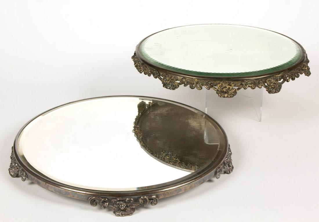 VICTORIAN SILVER-PLATED MIRROR PLATEAUS, LOT OF TWO: VICTORIAN SILVER-PLATED MIRROR PLATEAUS, LOT OF TWO, circular examples, each with beveled glass, one example retains label to the underside. Late 19th/early 20th century. 12" and 14" D. Good as-found 