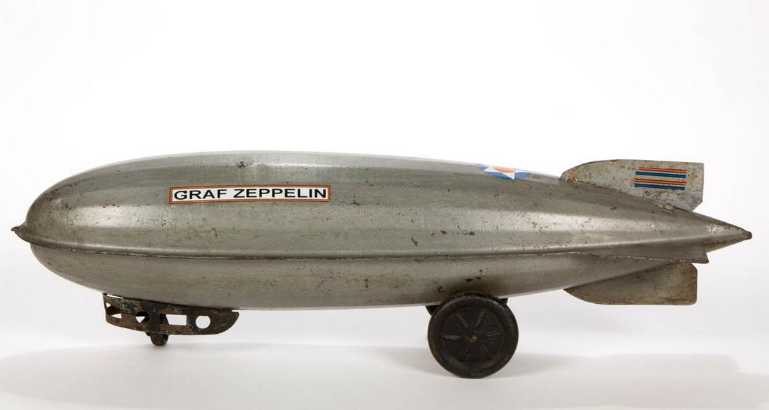 VINTAGE STEELCRAFT GRAFF ZEPPELIN PULL TOY: VINTAGE STEELCRAFT GRAFF ZEPPELIN PULL TOY, silver body with polychrome decals. Circa 1930. 24 1/2" LOA.Good overall visual condition. Decals likely replaced and other possible restoration to surface.