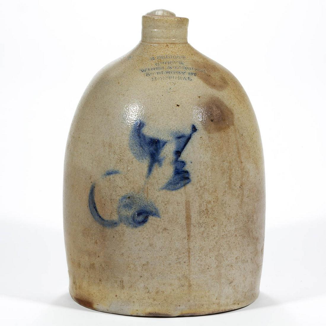 STAMPED "E. ELLIOTT / GROCER / WINES & LIQUORS / 59: STAMPED "E. ELLIOTT / GROCER / WINES & LIQUORS / 59 BLEURY ST / MONTREAL", CANADA DECORATED STONEWARE JUG, salt-glazed, "2" gallon capacity mark, beehive form with plain rim and strap handle. Brushed 