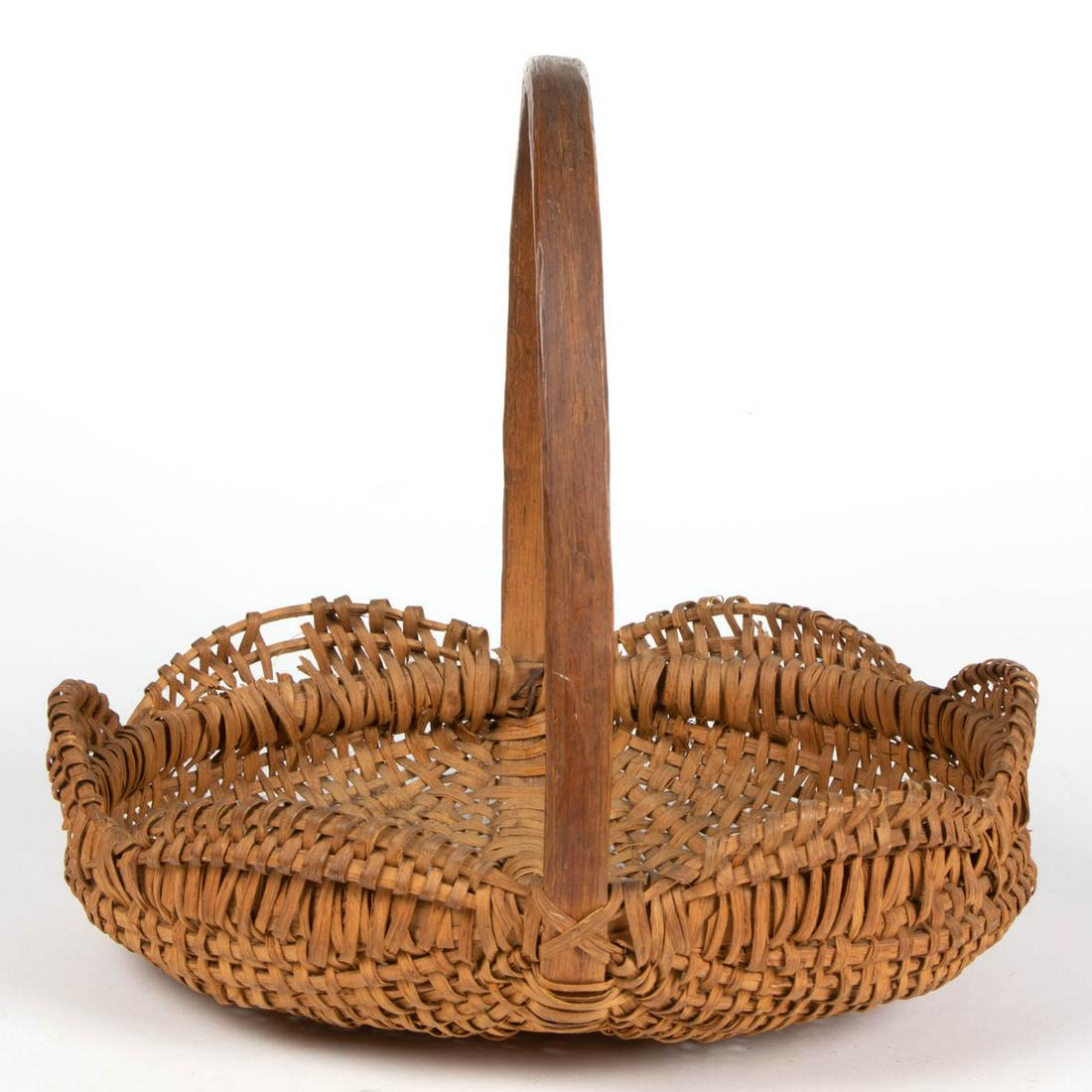 VIRGINIA WOVEN-SPLINT FLOWER / HERB BASKET: VIRGINIA WOVEN-SPLINT FLOWER / HERB BASKET, white oak, circular form with high arched handle and scalloped rim. Dry natural surface. First quarter 20th century. 13 1/2" HOA, 4" H rim, 14" W rim. Good 