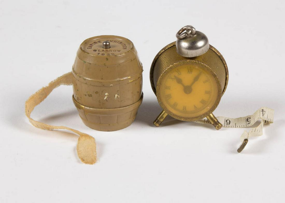 VINTAGE FIGURAL METAL TAPE MEASURES, LOT OF TWO: VINTAGE FIGURAL METAL TAPE MEASURES, LOT OF TWO, comprising a brass alarm clock and a painted brass whiskey barrel marked for Wm. Younger Brewers, and the Empire Exhibition, Glasgow, 1938. First half 