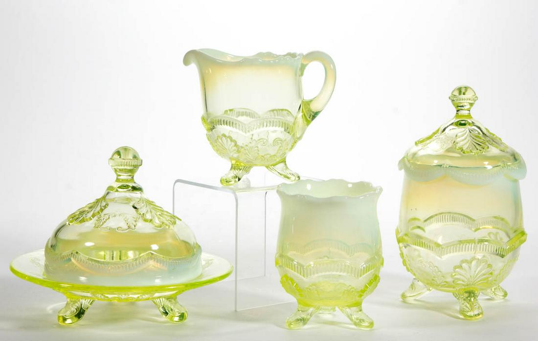MANILA / WREATH AND SHELL FOUR-PIECE TABLE SET: MANILA / WREATH AND SHELL FOUR-PIECE TABLE SET, Vaseline (reacts under black light) opalescent, comprising a covered butter dish, covered sugar bowl, creamer, and spooner. Model Flint Glass Co. 1899-1