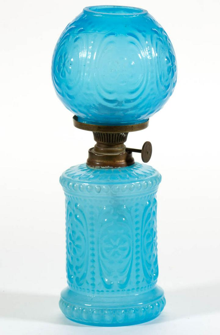EMBOSSED FLORAL AND SCROLL MINIATURE LAMP: EMBOSSED FLORAL AND SCROLL MINIATURE LAMP, translucent blue opaline, cylinder-form font with slightly concave banded medial, matching pattern deeper blue opaline ball-form shade, period collar. Fitted