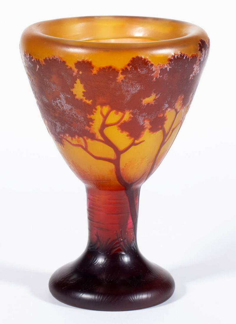 DAUM NANCY LANDSCAPE CAMEO ART GLASS VASE: DAUM NANCY LANDSCAPE CAMEO ART GLASS VASE, ruby to amber, conical-form bowl with a folded-in rim, decoration depicting a lakeside scene with trees and a grassy ground, signed "DAUM/NANCY" with the Cro