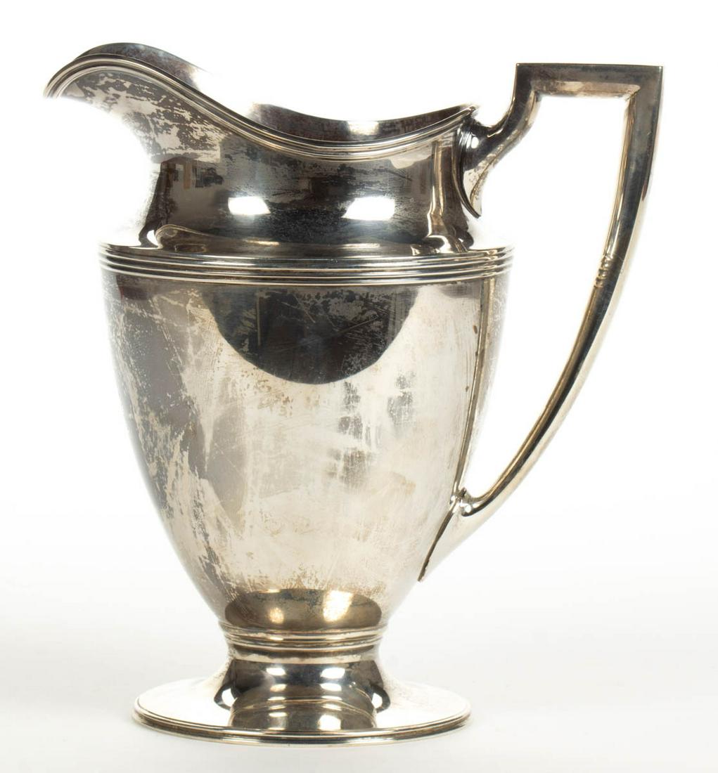 TIFFANY & CO. "HAMILTON" STERLING SILVER WATER PITCHER: TIFFANY & CO. "HAMILTON" STERLING SILVER WATER PITCHER, having a Neoclassical-form well with reeded accents and an angular handle, raised on a round foot, engraved "SWC" to side and "M.L.W - S.C.W / 1