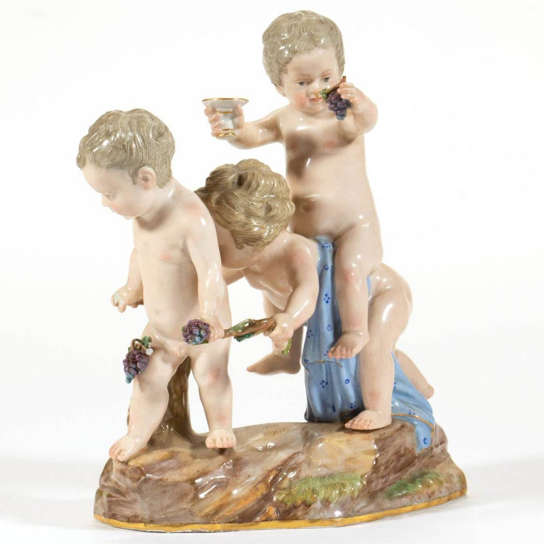 GERMAN MEISSEN CHERUB / PUTTI FIGURAL GROUP: GERMAN MEISSEN CHERUB / PUTTI FIGURAL GROUP, having polychrome and gilt hand-painted decoration, depicting three rambunctious naked children on a rock-molded base, some holding grapes. Having undergla