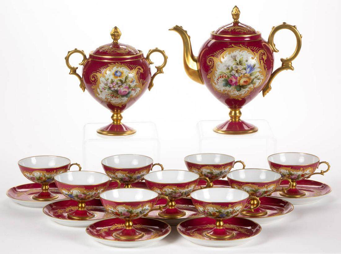 FRENCH PORCELAIN 20-PIECE PARTIAL TEA SET: FRENCH PORCELAIN 20-PIECE PARTIAL TEA SET, comprising a footed teapot, a covered sugar, and nine cup and saucer sets, each featuring polychrome hand-painted floral bouquet design on magenta ground wit