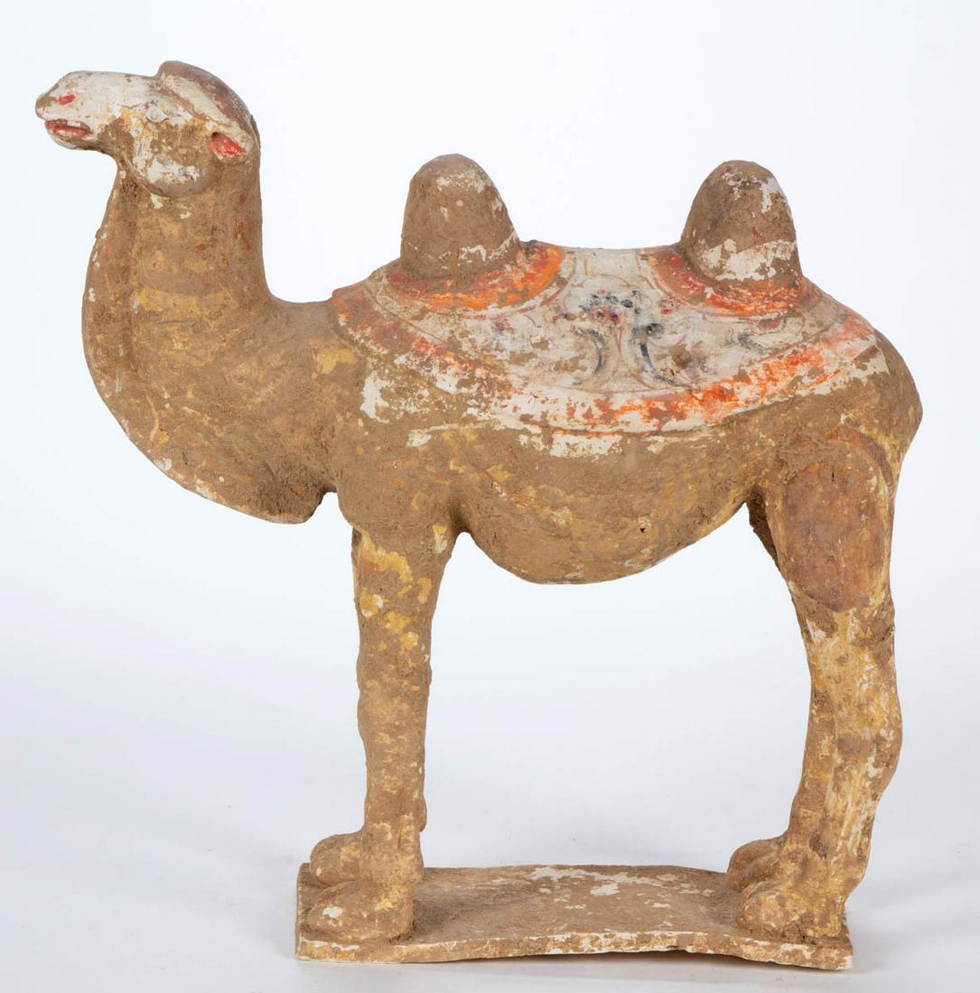 CHINESE BATRIAN CAMEL EARTHENWARE TOMB FIGURE: CHINESE BATRIAN CAMEL EARTHENWARE TOMB FIGURE, having remnants of pigment, camel with two humps wearing a saddle, standing at attention on a rectangular base. A descriptive sheet from Arch Angel Antiq