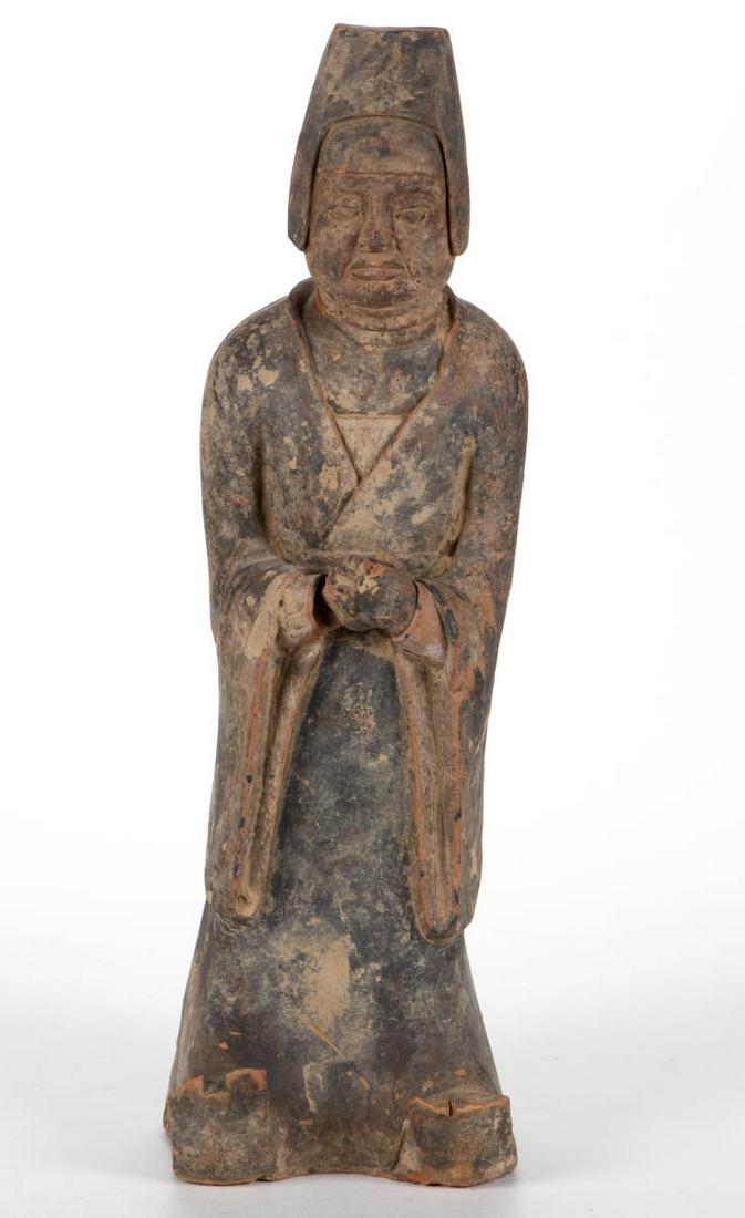 CHINESE EARTHENWARE TOMB FIGURE: CHINESE EARTHENWARE TOMB FIGURE, having remnants of pigment, wearing a tapered hat, a long robe, and shoes with toes curling upward. An undated descriptive sheet from Arch Angel Antiques, Hong Kong, a