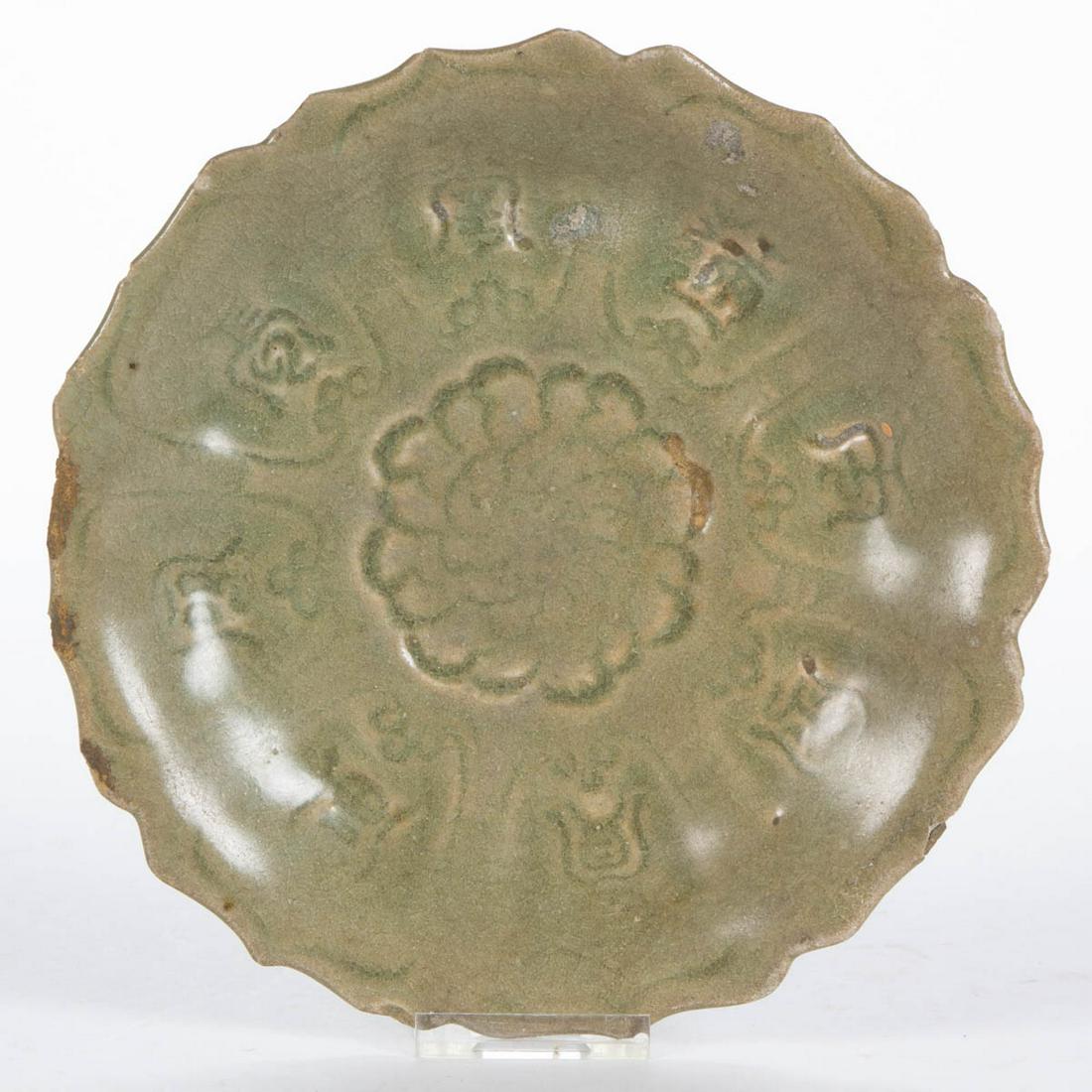 CHINESE CELADON EARTHENWARE FOOTED DISH: CHINESE CELADON EARTHENWARE FOOTED DISH, having scalloped rim featuring central peony-like flower to center encircled by eight characters, reportedly translates to "Long life, wealth and honor, gold a
