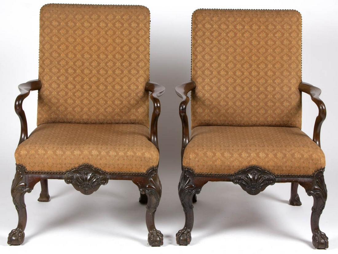 PAIR OF GEORGE II CARVED MAHOGANY LIBRARY CHAIRS: PAIR OF GEORGE II CARVED MAHOGANY LIBRARY CHAIRS, featuring serpentine arms and cabriole legs with shell-carved knees and ball-and-claw feet, rear legs ending in hoofed feet. Retains an early surface 