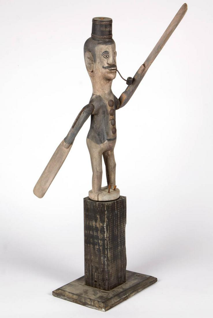 FOLK ART CARVED AND PAINTED WHIRLIGIG: FOLK ART CARVED AND PAINTED WHIRLIGIG, depicting a man with a pipe, applied to a wooden base. 20th century. 34" HOA. Very good overall condition, with expected weathering and wear. Provenance: From a 