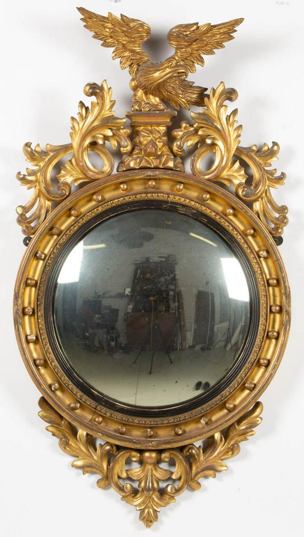 AMERICAN CLASSICAL GILTWOOD GIRANDOLE WALL MIRROR: AMERICAN CLASSICAL GILTWOOD GIRANDOLE WALL MIRROR, spread-wing eagle flanked by Rococo-style foliate devices above the convex mirror plate, pierced foliate work below. Likely original surface. 19th ce