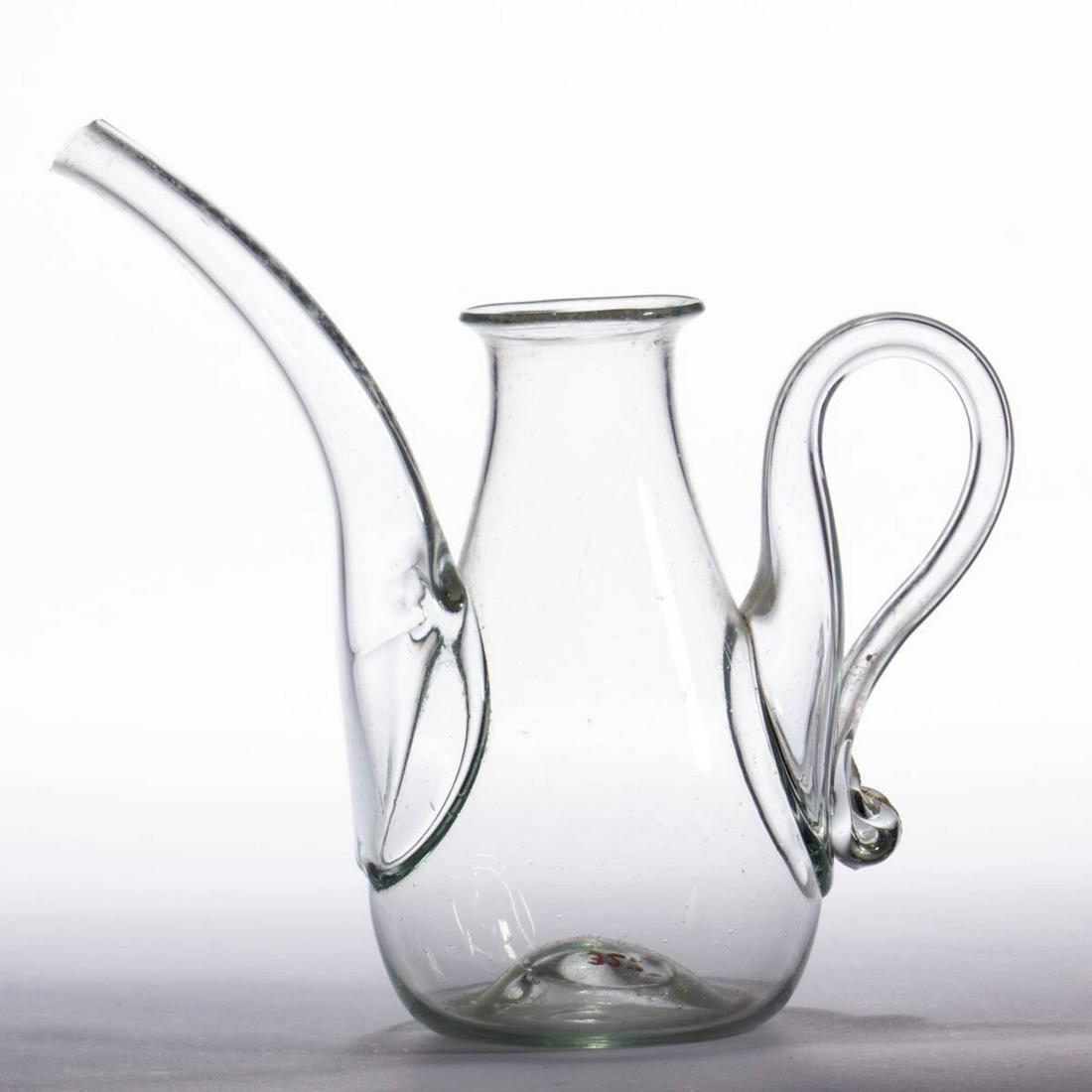 FREE-BLOWN LAMP FILLER / FEEDER: FREE-BLOWN LAMP FILLER / FEEDER, pale aquamarine, baluster form body with an applied elongated spout, and applied elegantly curled hollow handle with a curl to the lower terminal of the handle, kick-u