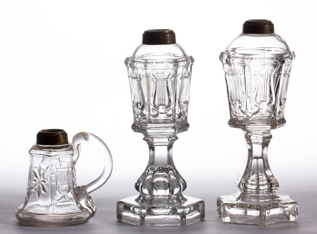 PRESSED AND BLOWN-MOLDED LYRE / HARP WHALE OIL / FLUID: PRESSED AND BLOWN-MOLDED LYRE / HARP WHALE OIL / FLUID LAMPS, LOT OF THREE, colorless, comprising two stand lamps with each being raised on a baluster-form stem with one having a hexagonal base and th