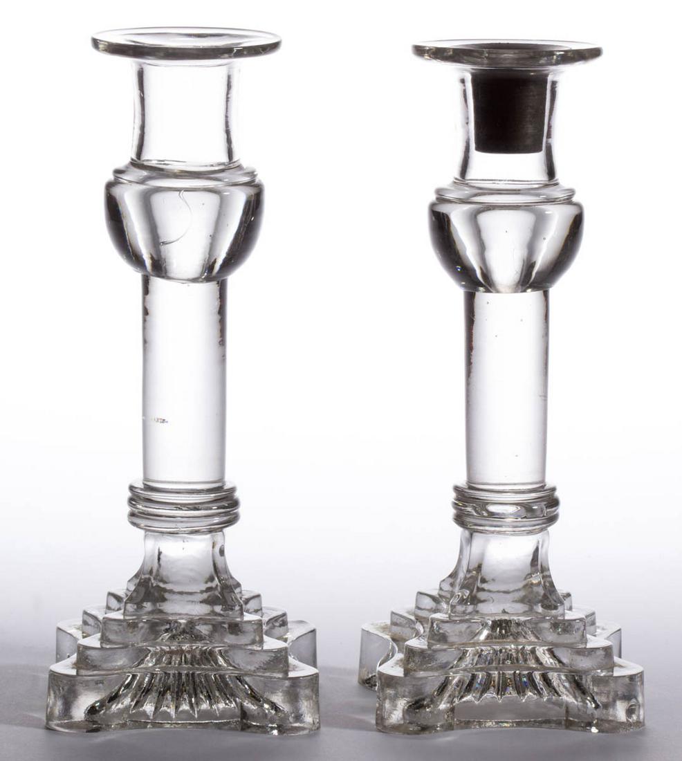 FREE-BLOWN AND PRESSED PAIR OF CANDLESTICKS: FREE-BLOWN AND PRESSED PAIR OF CANDLESTICKS, colorless, each deep socket with a flanged rim and applied bulbous base with upper ring, raised on a solid cylindrical shaft, three-step quatrefoil base, o