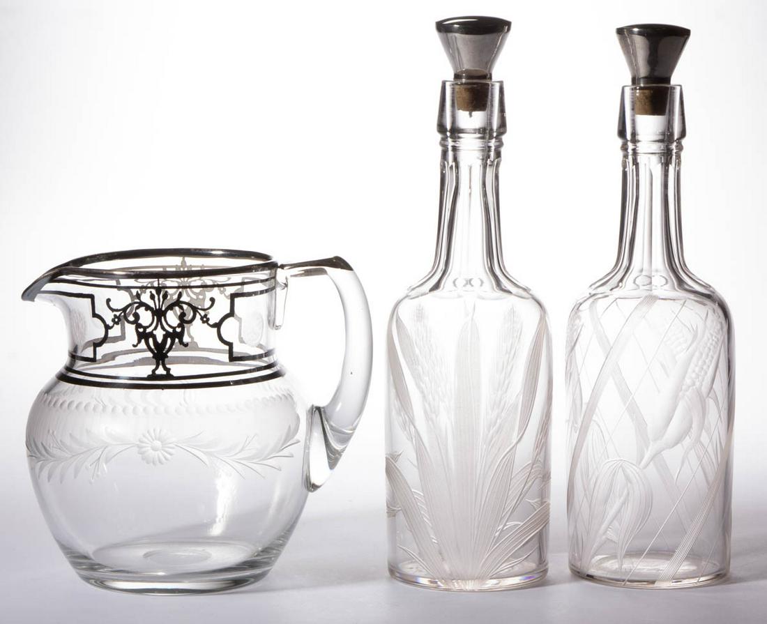 ASSORTED ENGRAVED GLASS DRINKING ARTICLES, LOT OF THREE: ASSORTED ENGRAVED GLASS DRINKING ARTICLES, LOT OF THREE, colorless, comprising a pair of decanters depicting wheat and corn with original stoppers marked "STERLING" with Watson Co. hallmarks, and a He