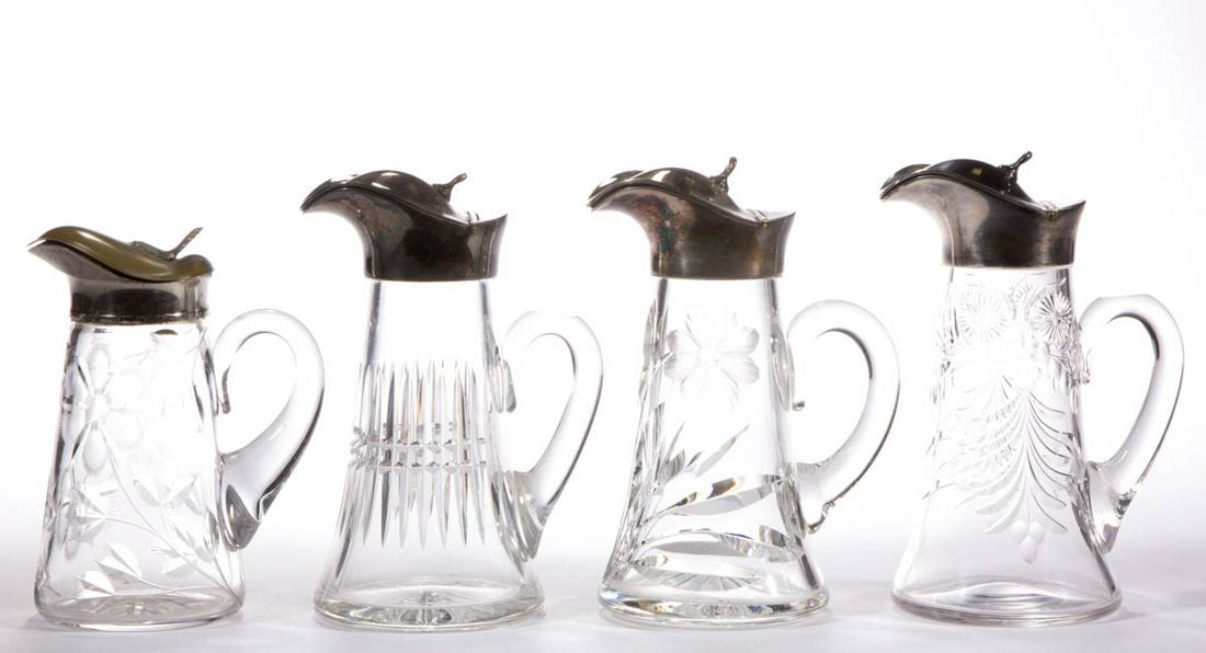ASSORTED CUT / ENGRAVED GLASS SYRUP PITCHERS, LOT OF: ASSORTED CUT / ENGRAVED GLASS SYRUP PITCHERS, LOT OF FOUR, colorless, comprising three with floral patterns, and one with a prism band, each having a period lid. Various makers. Late 19th/first quarte