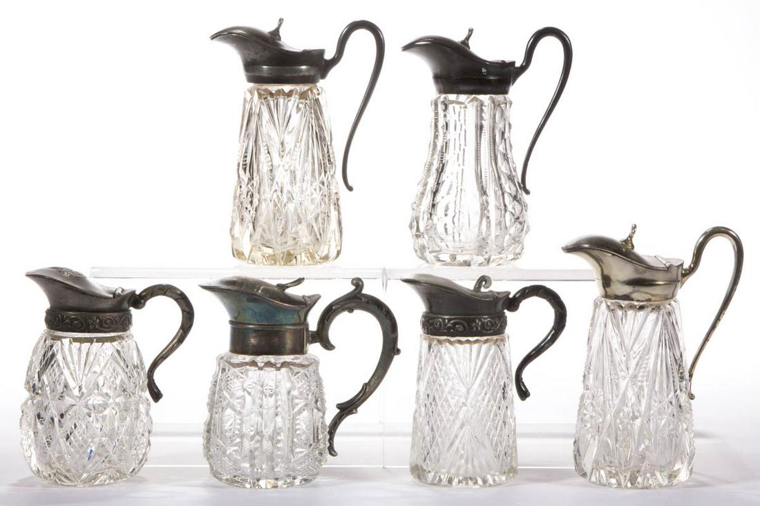 ASSORTED CUT GLASS SYRUP PITCHERS, LOT OF SIX: ASSORTED CUT GLASS SYRUP PITCHERS, LOT OF SIX, colorless, including two having Diamonds and Fans patterns, two with Chevron motifs, and a Zippered example, each having a period lid. Various makers. La
