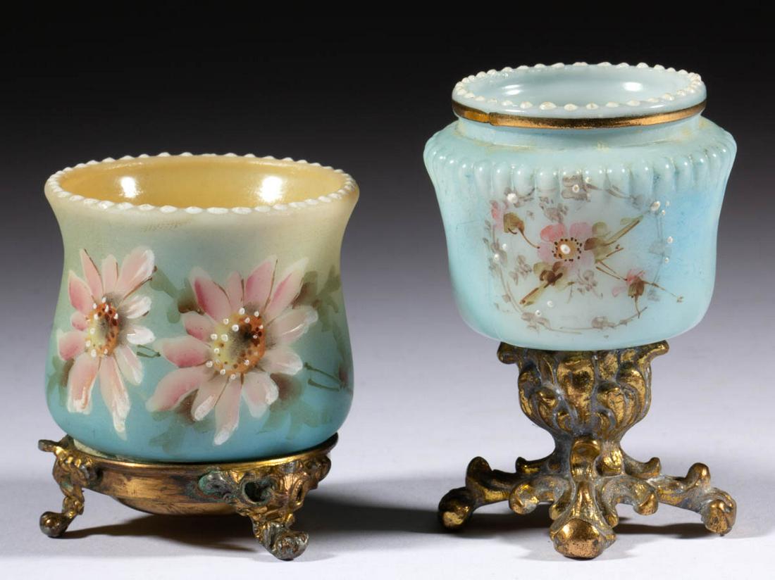 WAVE CREST ENAMEL-DECORATED PEDESTAL TOOTHPICK HOLDERS,: WAVE CREST ENAMEL-DECORATED PEDESTAL TOOTHPICK HOLDERS, LOT OF TWO, each having a beaded rim with blue ground and polychrome floral decoration, each having a cast-brass base with four feet. C. F. Monr