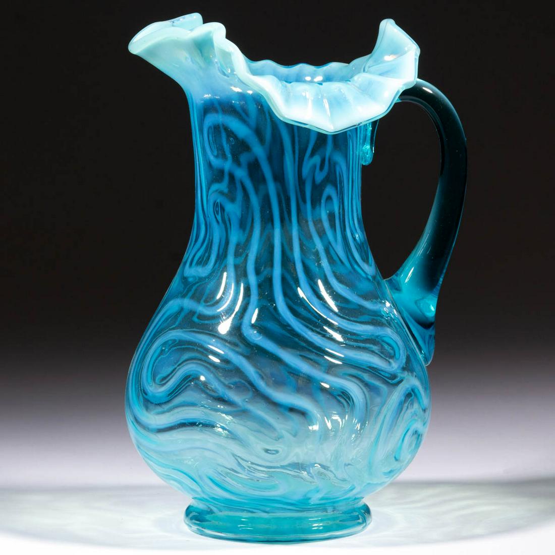 SWIRLING MAZE WATER PITCHER: SWIRLING MAZE WATER PITCHER, blue opalescent, tooled ruffled rim, applied blue handle. Jefferson Glass Co. Circa 1905. 10 5/8" HOA.Having a crack to the body in-line with the upper terminal of the han