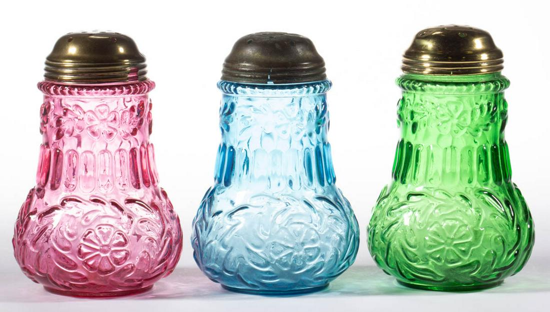 FLOWER MOLD SUGAR SHAKERS, LOT OF THREE: FLOWER MOLD SUGAR SHAKERS, LOT OF THREE, cranberry, blue, and green, each having a period lid. Beaumont Glass Co. Circa 1895. 5 1/4" H. Glass undamaged; lids each having splitting, one lid having a sm