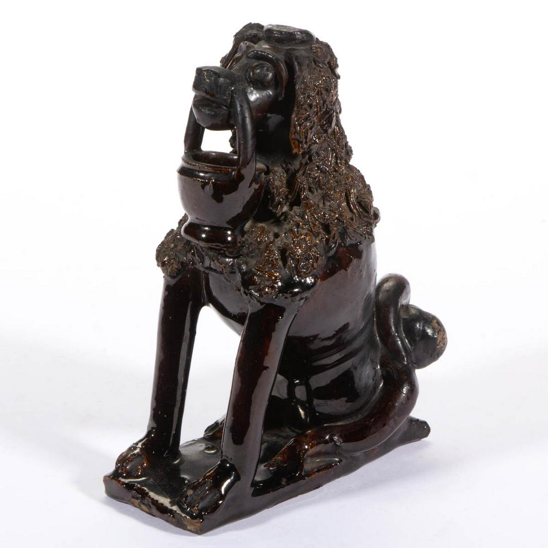 FOLK ART EARTHENWARE / REDWARE FIGURAL POODLE QUILL: FOLK ART EARTHENWARE / REDWARE FIGURAL POODLE QUILL HOLDER, lead- and manganese-glazed, seated form with open front legs, holding a basket in his open mouth, hole to top of head, delineated eyebrows a