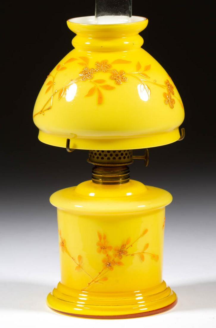 DECORATED CASED GLASS MINIATURE LAMP: DECORATED CASED GLASS MINIATURE LAMP, cased lemon yellow with orange enamel and gilt floral and butterfly decoration, cylinder-form font with wide concave medial band, matching decorated umbrella-form