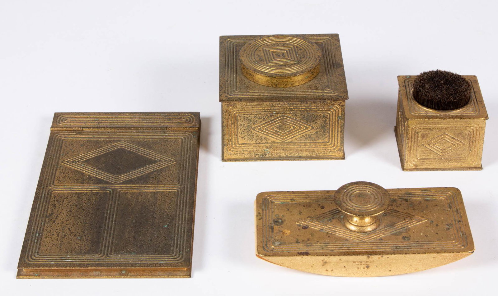 TIFFANY STUDIOS GRADUATE BRONZE FOUR-PIECE DESK SET: TIFFANY STUDIOS GRADUATE BRONZE FOUR-PIECE DESK SET, comprising a calendar retaining the original paper, stamped to the interior "HOWARD P. MOORE/GENERAL MANAGER/1919-1926/WITH ESTEEM AND AFFECTION/FR