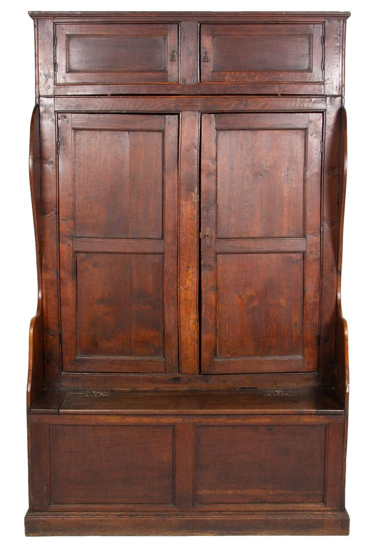BRITISH REGIONAL OAK AND ELM BACON SETTLE BENCH: BRITISH REGIONAL OAK AND ELM BACON SETTLE BENCH, high-back form of two-piece construction, the simple applied cornice over two hinged doors, above two hinged doors, over hinged rectangular lid, shaped