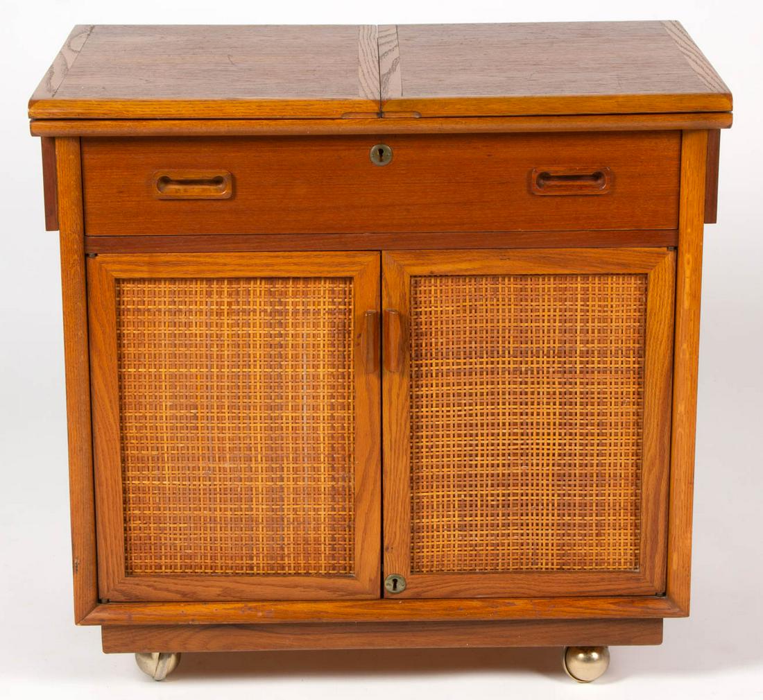 AMERICAN MID-CENTURY MODERN OAK AND TEAKWOOD COCKTAIL /: AMERICAN MID-CENTURY MODERN OAK AND TEAKWOOD COCKTAIL / DRINK CART, with rattan doors and hinged folding top, on casters. Possibly Lane. Third quarter 20th century. 29 3/4" H, 31" W, 19 1/2" D. Very g