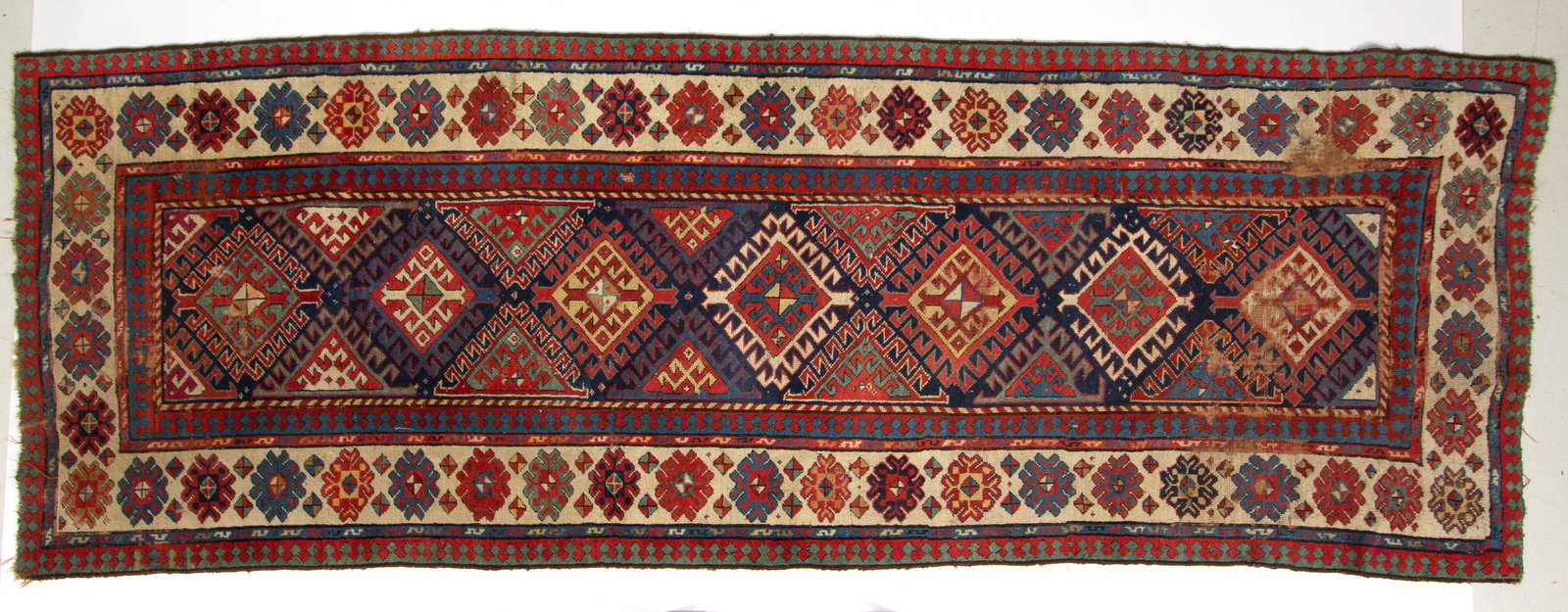 ANTIQUE CAUCASIAN KAZAK TRIBAL RUG / RUNNER: ANTIQUE CAUCASIAN KAZAK TRIBAL RUG / RUNNER, body colors, featuring seven central medallions. First quarter 20th century. 9' 2" x 3' 6 3/4". Good as-found condition, scattered losses to edges and trim