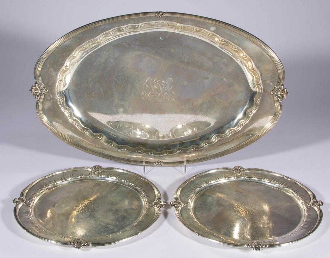 TIFFANY & CO. STERLING SILVER THREE-PIECE TRAY SET: TIFFANY & CO. STERLING SILVER THREE-PIECE TRAY SET, comprising a larger ovoid example and two round examples, each featuring a reeded scroll rim with foliate motifs, scalloped inner rim, and engraved