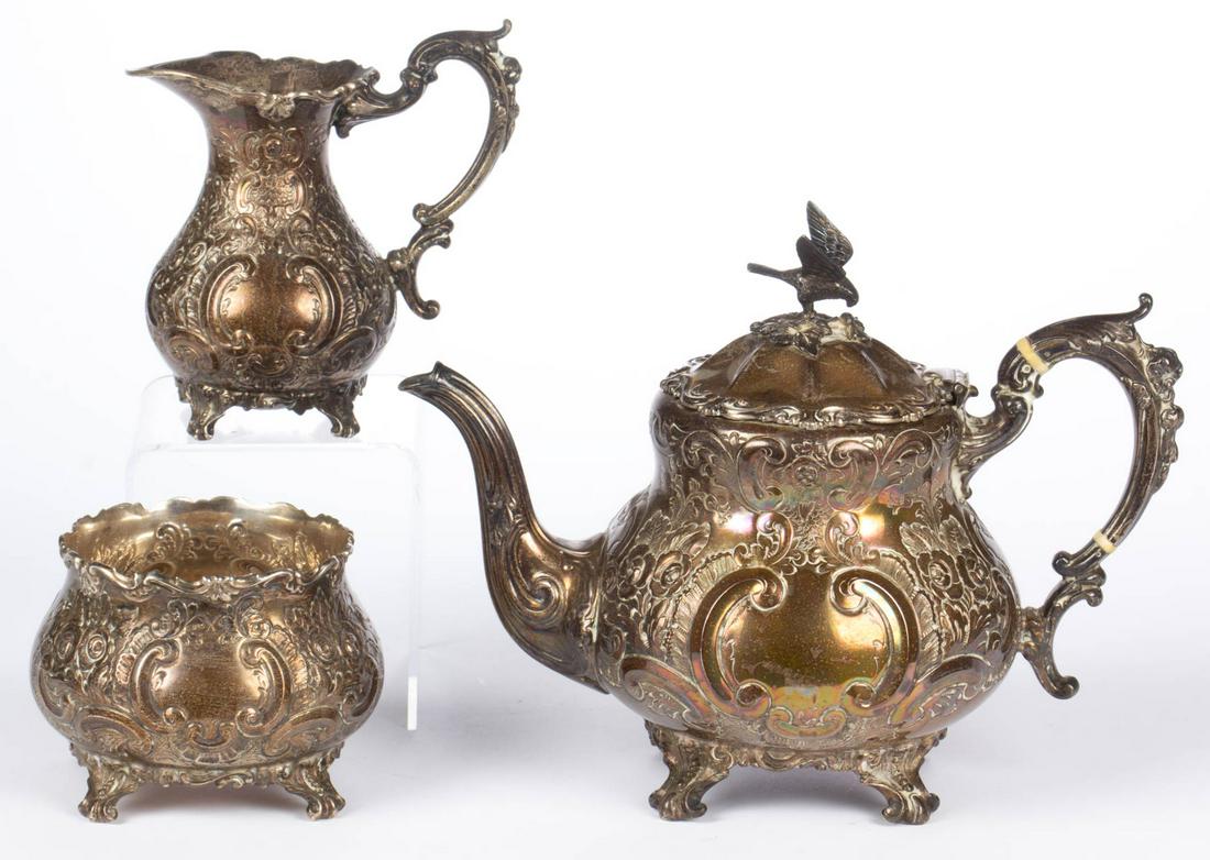 ENGLISH ROCOCO-STYLE STERLING SILVER THREE-PIECE TEA: ENGLISH ROCOCO-STYLE STERLING SILVER THREE-PIECE TEA SERVICE, comprising a teapot, a creamer, and a waste bowl, each with repousse and chased decoration featuring flowers, scrolls and leaves, raised o