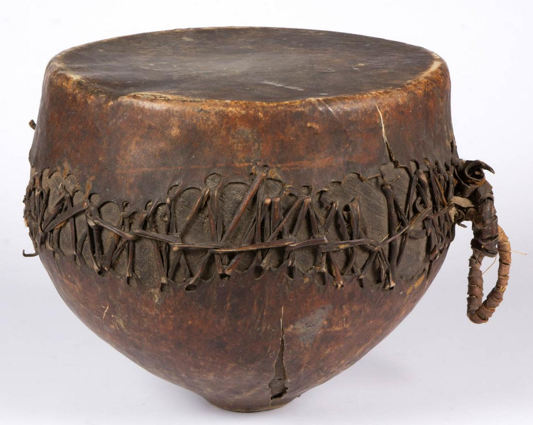 AFRICAN TRIBAL DRUM: AFRICAN TRIBAL DRUM, bulbous form, with likely original covering. Old surface with warm color. 20th century. 13" H, 14" D. Very good overall condition, old crack to covering, scattered minor losses, a