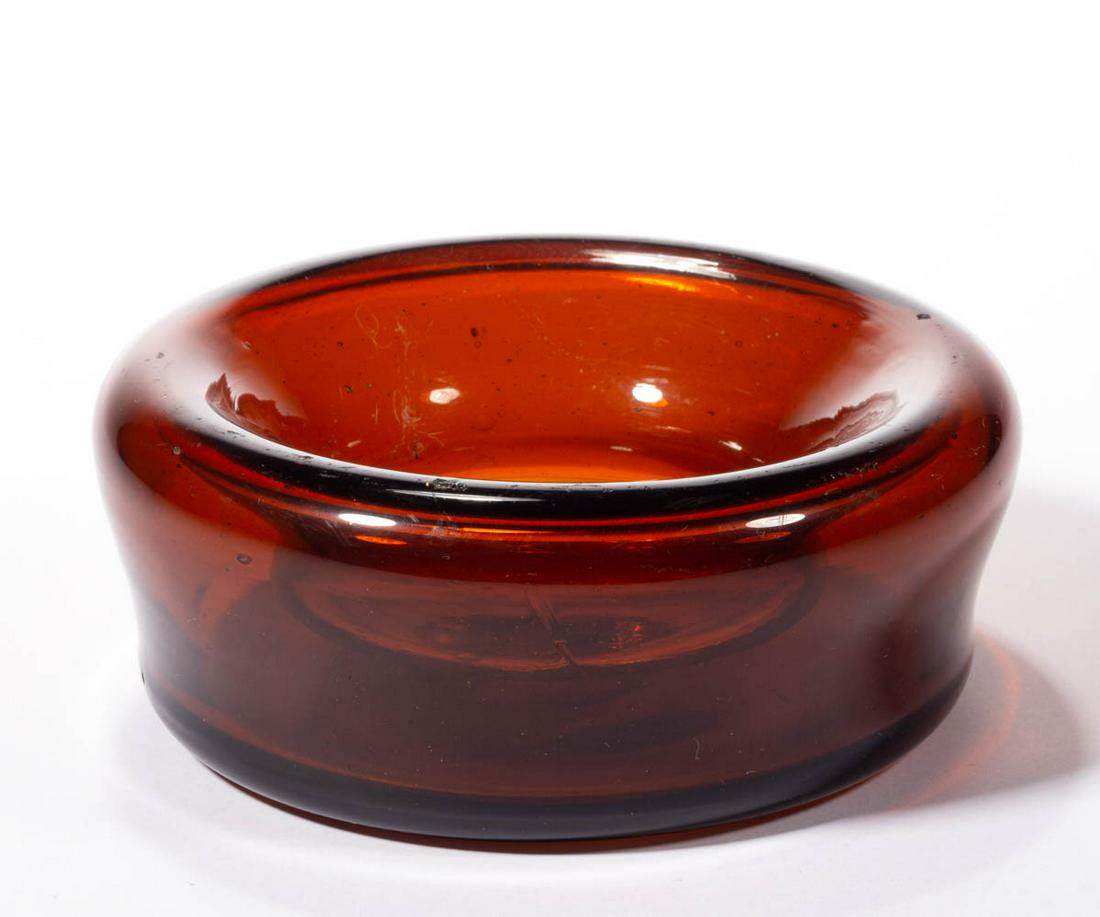 FREE-BLOWN GLASS SPITTOON-TYPE VESSEL: FREE-BLOWN GLASS SPITTOON-TYPE VESSEL, red amber, circular form with a folded-in rim, faint rough pontil mark. Maker unverified. First half 19th century. 2 1/8" H, 5 1/2" D. Very good to excellent con