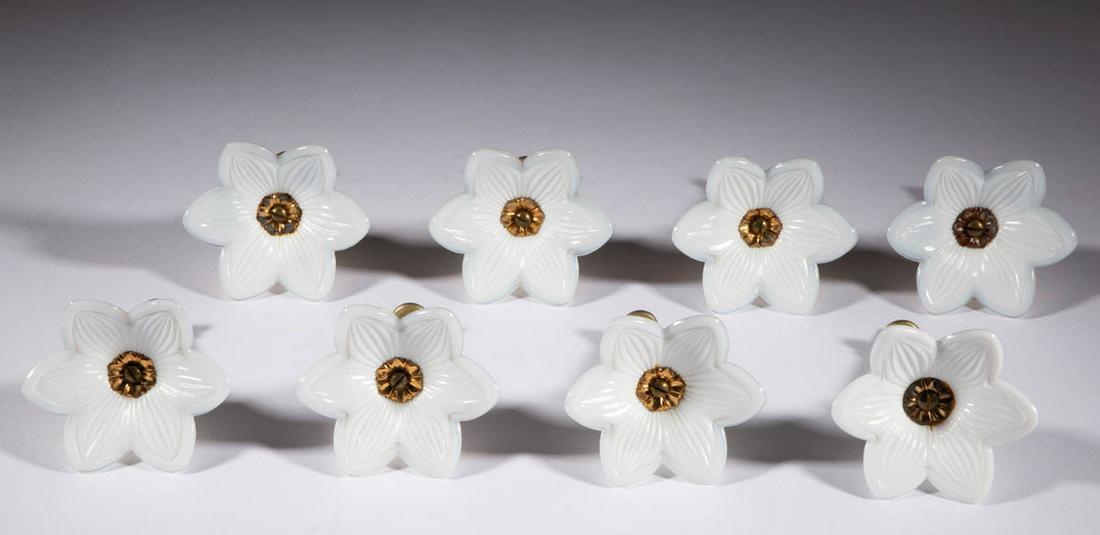 PRESSED LILY GLASS CURTAIN PINS / TIE BACKS, LOT OF: PRESSED LILY GLASS CURTAIN PINS / TIE BACKS, LOT OF EIGHT, opaque white with fiery opalescent edges, each in the form of a six-petal blossom with a brass shank. Maker unverified. 19th century. 3 1/2" 