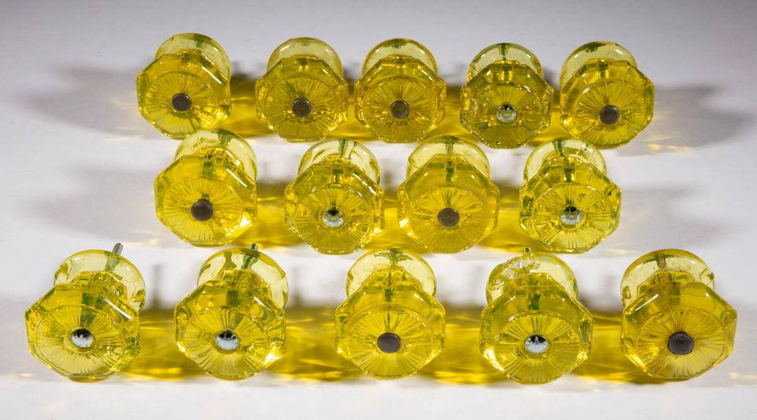 EARLY PRESSED FURNITURE KNOBS, LOT OF 14: EARLY PRESSED FURNITURE KNOBS, LOT OF 14, deep canary yellow (reacts under black light), each large size with an octagonal, rayed face and center hole for the mounting shank, one with a period metal s