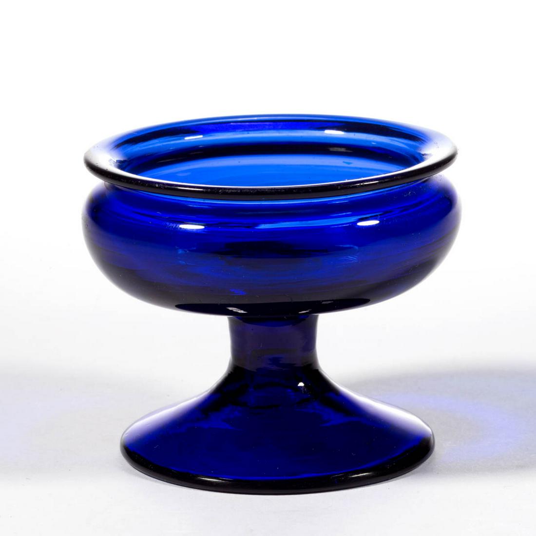 FREE-BLOWN FOOTED OPEN SALT: FREE-BLOWN FOOTED OPEN SALT, deep cobalt blue, shallow bowl with everted rim, raised on a short cylindrical stem and conical foot open into stem, rough pontil mark. 1800-1840. 2" H, 2 1/2" D rim, 2 1/