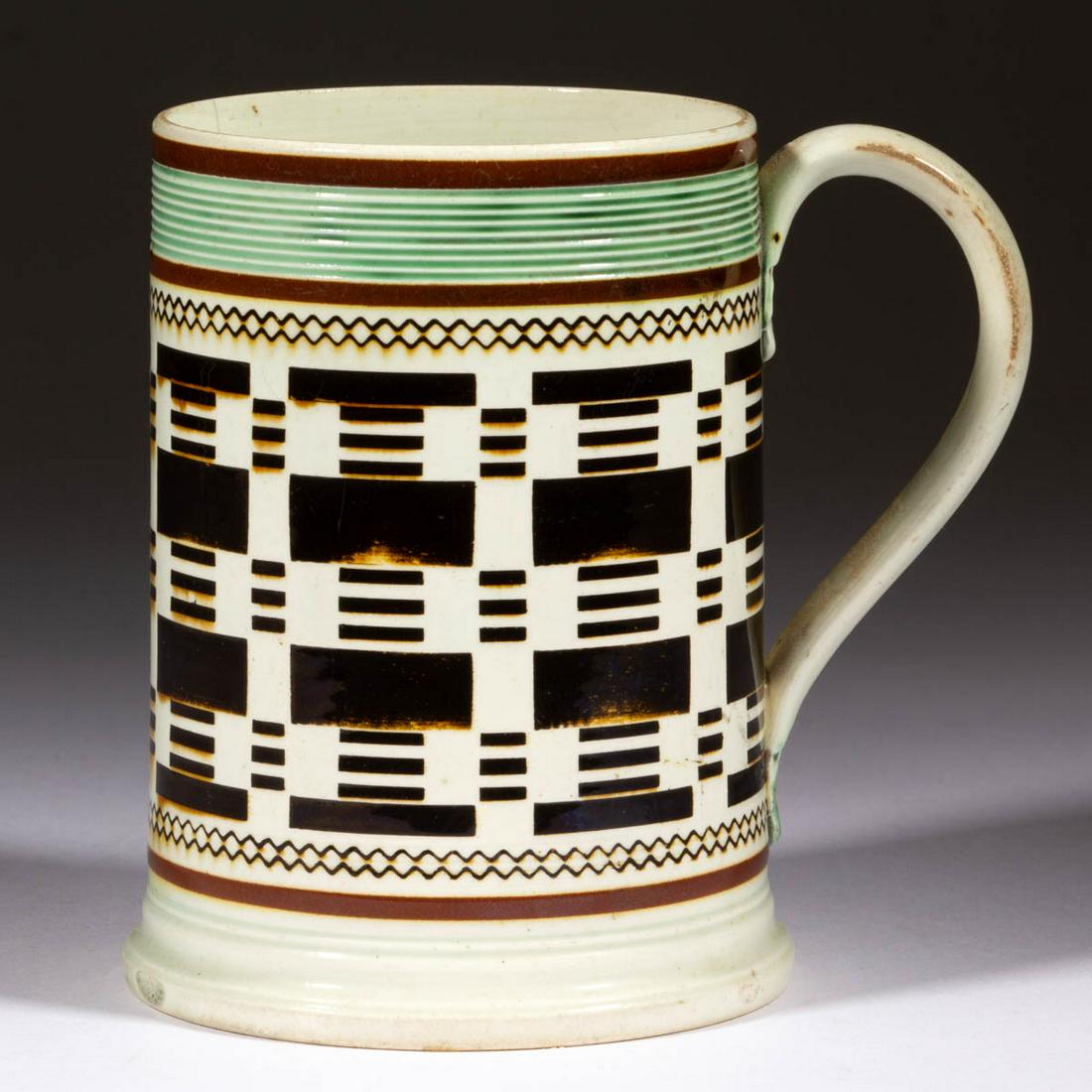 BRITISH PEARLWARE ENGINE-TURNED DIPPED WARE / MOCHA: BRITISH PEARLWARE ENGINE-TURNED DIPPED WARE / MOCHA CERAMIC MUG, approximately one-pint capacity, cylindrical form having applied strap handle with molded foliate terminals, featuring inlaid dashed an