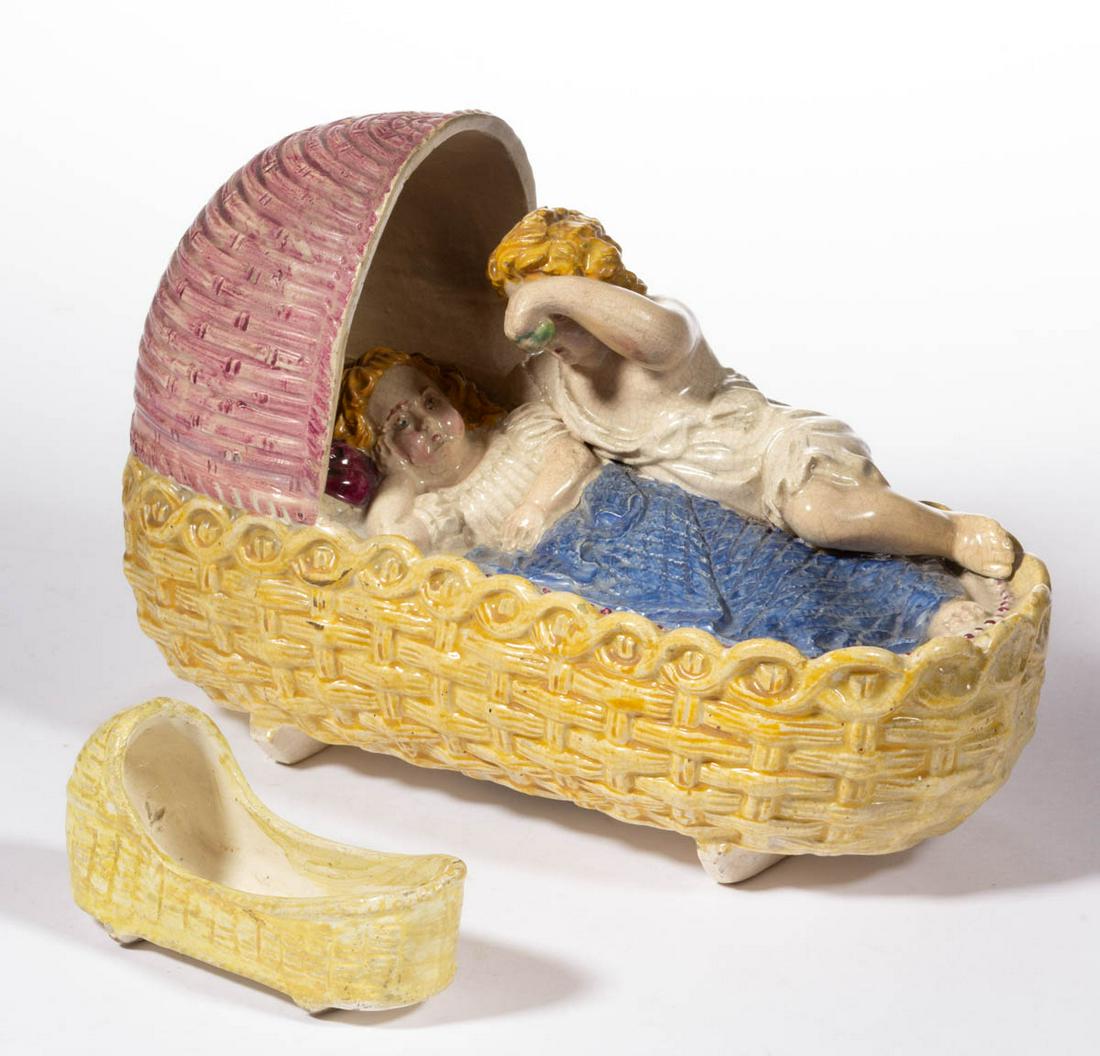 CONTINENTAL CERAMIC CHILDREN FIGURAL GROUP: CONTINENTAL CERAMIC CHILDREN FIGURAL GROUP, having polychrome hand-painted decoration, featuring a molded basketweave cradle with two rockers, having two children, one awake tucked under covers and th
