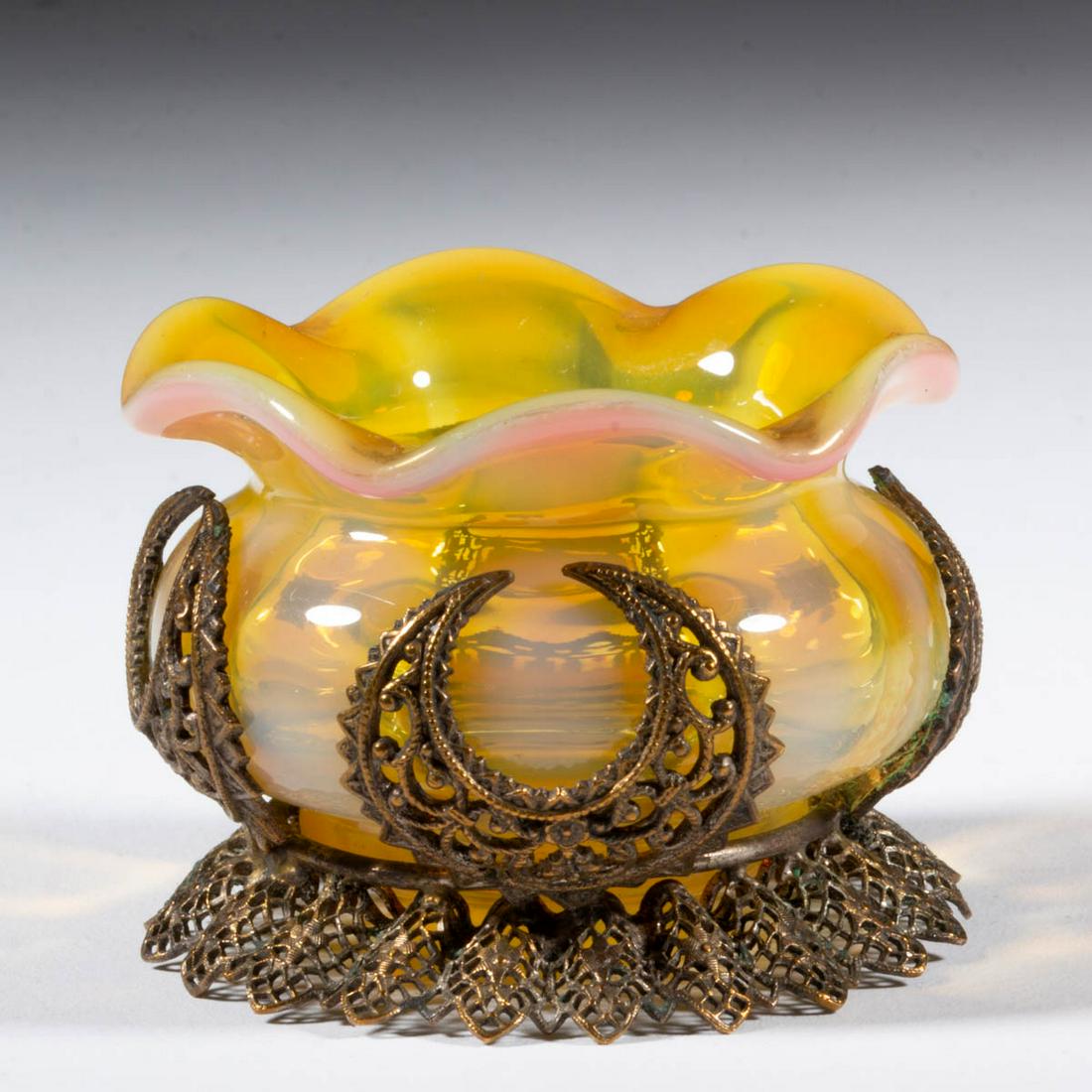 MONOT-STUMPF, PANTIN, RIB-OPTIC OPEN SALT: MONOT-STUMPF, PANTIN, RIB-OPTIC OPEN SALT, light apricot striped opalescent, circular form with ruffled rim, original filigree frame with crescent moons, polished pontil mark. France. Fourth quarter 1