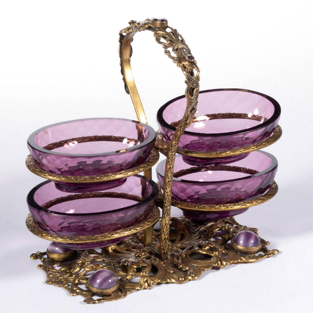 INTAGLIO GLASS OPEN SALTS IN STAND: INTAGLIO GLASS OPEN SALTS IN STAND, amethyst, four matching ovoid salts with a diamond pattern to the side and depicting a pheasant to the base, all fitted in a gilt filigree stand with applied jewels