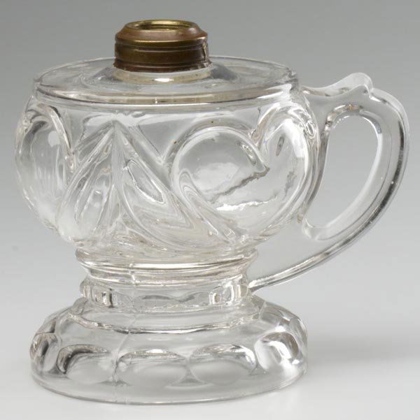 HEART FOOTED FINGER LAMP: HEART FOOTED FINGER LAMP, colorless, No. 1 Taplin-Brown collar. Tarentum Glass Co. 5 3/8" h to top of collar, 4 1/8" dia base. Literature: Thuro I, p. 260a.Provenance: Collection of Bill Courter.