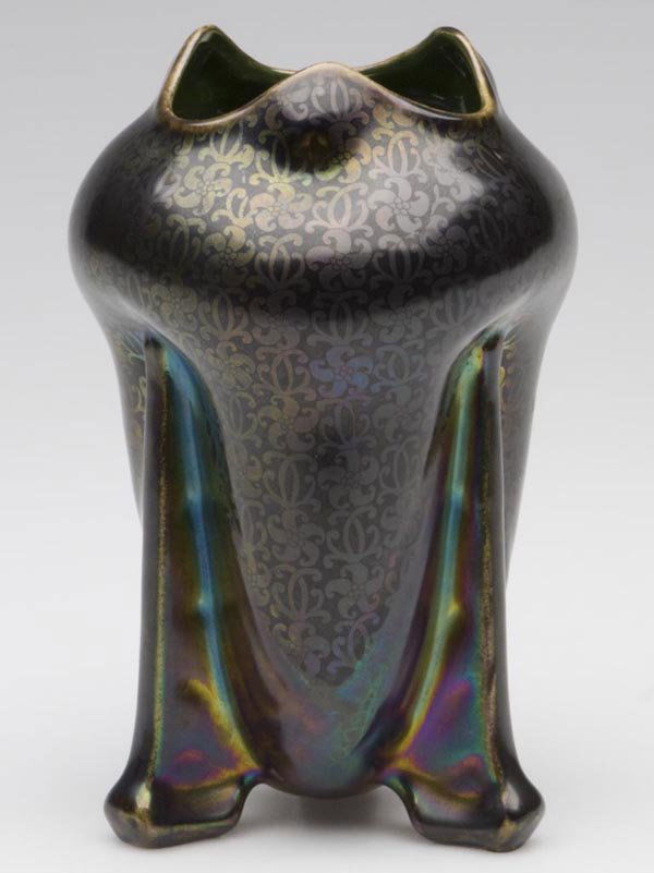 CONTINENTAL ART POTTERY VASE: CONTINENTAL ART POTTERY VASE, iridescent glaze, over tone-on-tone floral design, green interior, pinched form with three integral legs, impressed marks under base including "2", "P" and possibly "V".