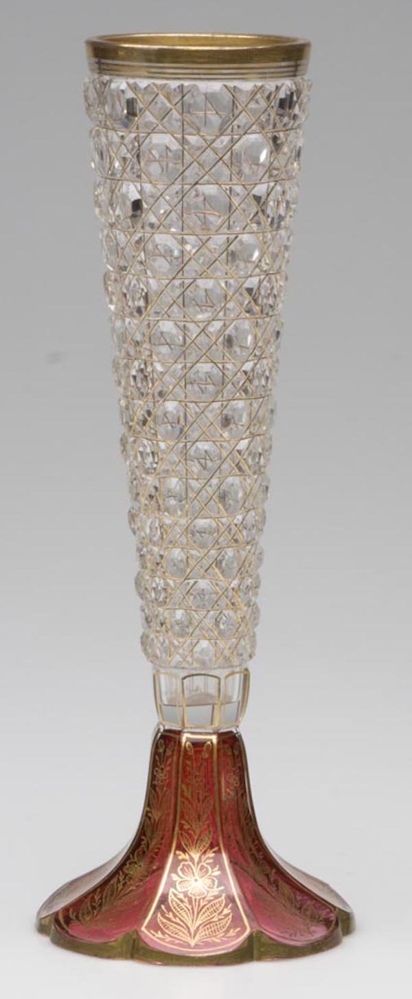 CUT AND STAINED GLASS VASE: CUT AND STAINED GLASS VASE, colorless with cranberry staining to foot, Cane pattern, gilt floral trim and floral decoration to foot. First half 20th century. 10 1/2" h. Provenance: From the collection