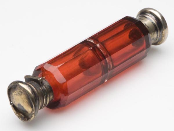 DOUBLE-END CRANBERRY GLASS SCENT BOTTLE: DOUBLE-END CRANBERRY GLASS SCENT BOTTLE, panel cut, unmarked silver fittings, lacking stopper. Fourth quarter 19th century. 4 3/4" l. Provenance: From the collection of Ellen and Don Roberts.
