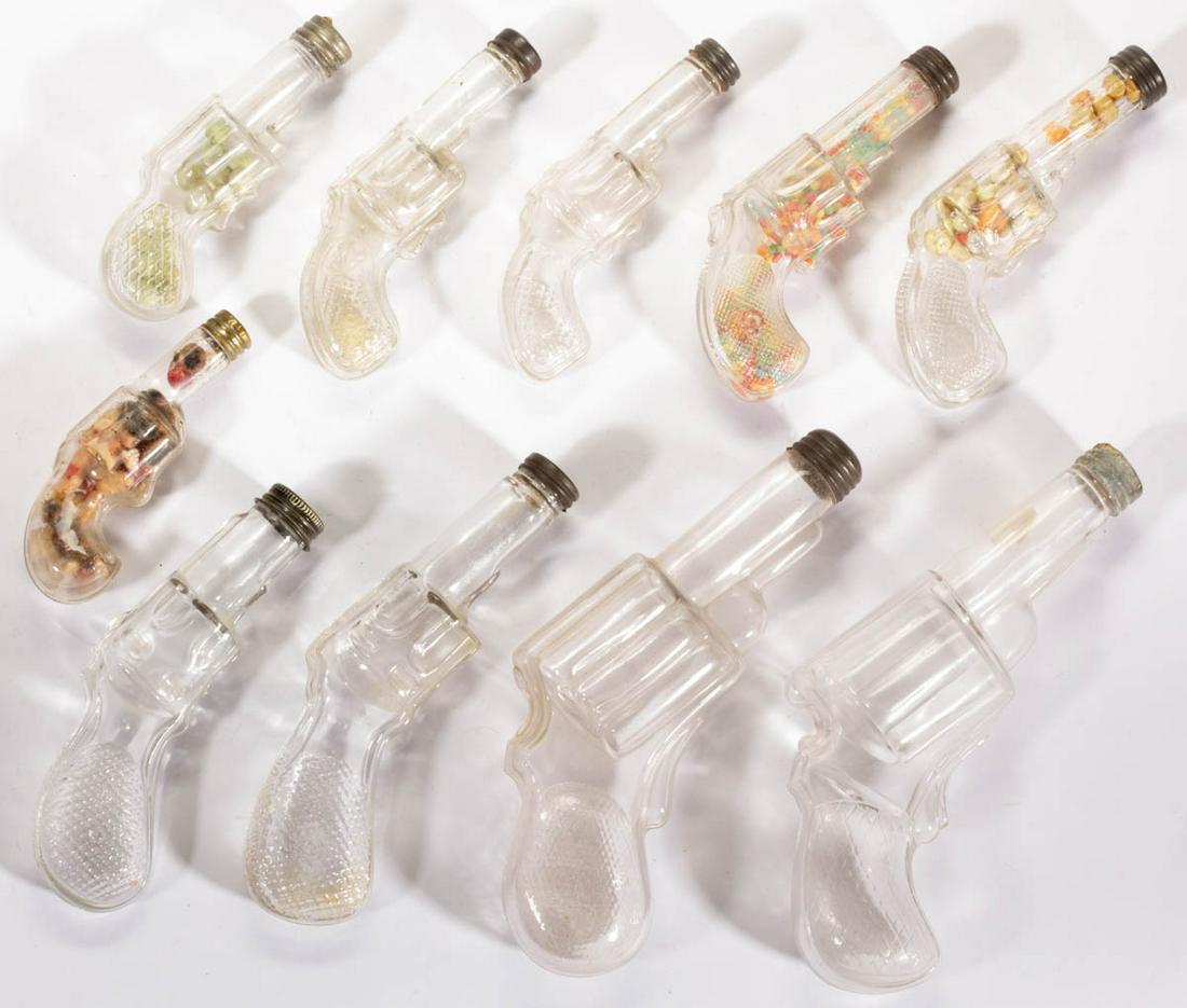 ASSORTED FIGURAL REVOLVER GLASS CANDY CONTAINERS, LOT: ASSORTED FIGURAL REVOLVER GLASS CANDY CONTAINERS, LOT OF TEN, colorless, including a V. G. Co., a small with a fancy grip, a Round Butt Revolver No. 2, and a Large Clear Revolver, each having a lid, s